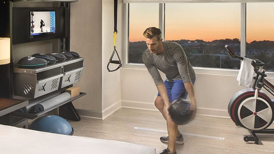 A man exercises with a medicine ball in Hilton's Five Feet to Fitness guest room