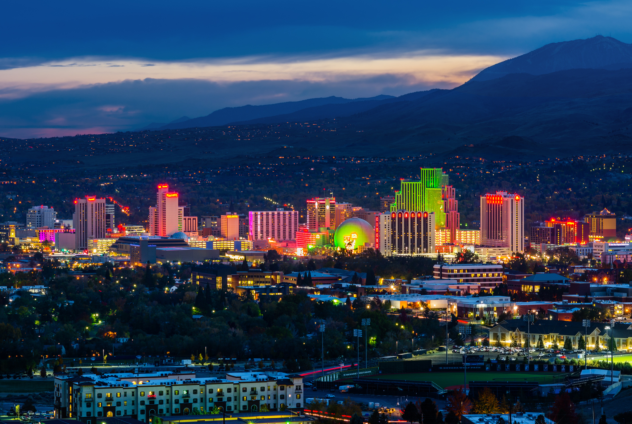 An aerial shot of Reno at night. Skyscrapers, most containing gaming, are lit up in neon colors.