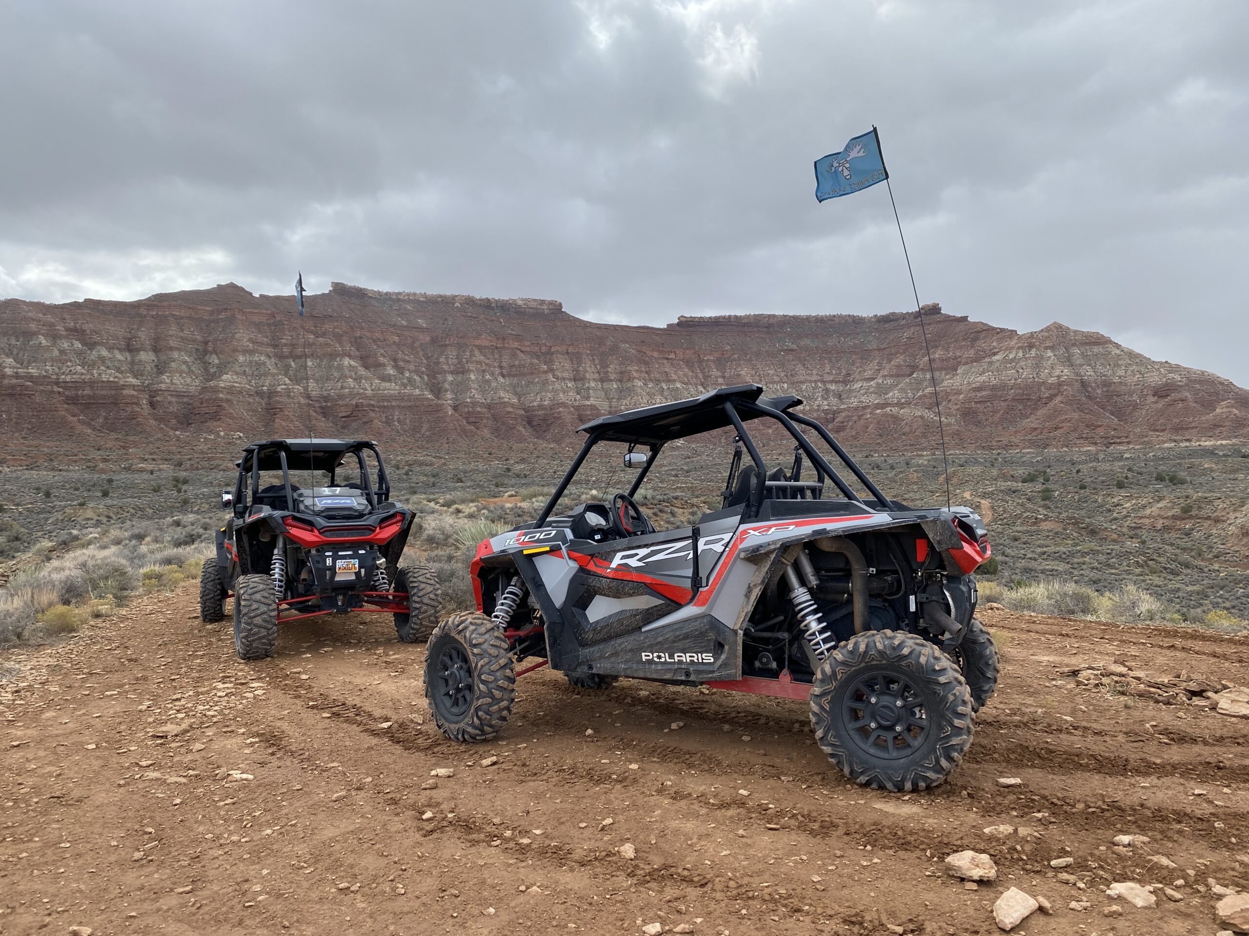 two utility terrain vehicles driving on dirt road