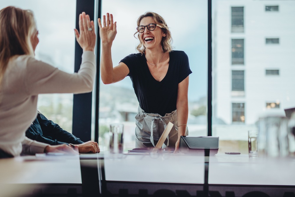 Businesswoman giving high five to another businesswoman in a meeting