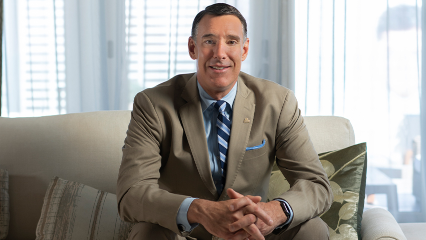 man in light brown suit sitting on couch