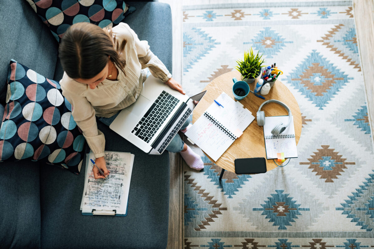 A woman working on a laptop while taking a survey on paper