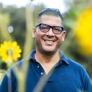 A portrait of Luis Arturo Aguilar. He is a Hispanic man with black glasses and a blue polo