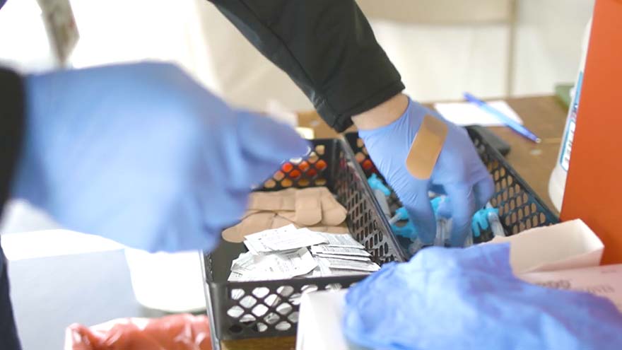 Gloved hands processing Covid tests