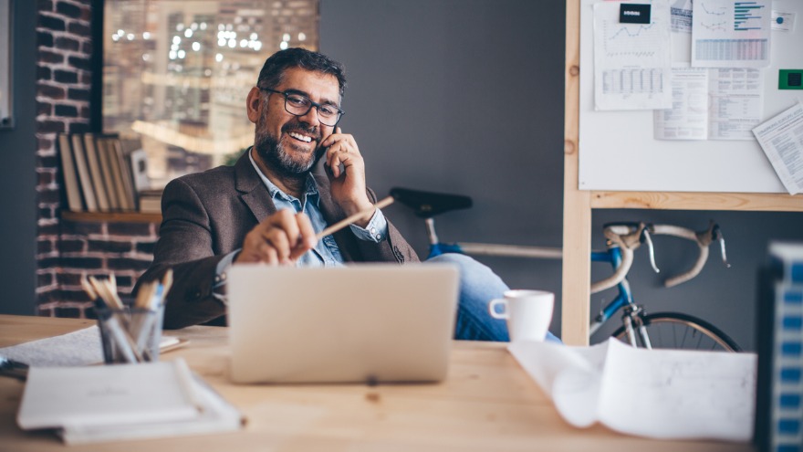 A man talking on the phone while working on his laptop