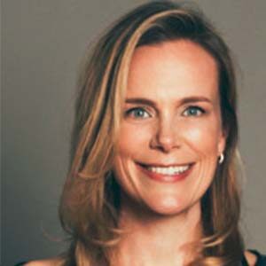 A portrait of Jennifer Collins. She is a white woman with wavy highlighted hair and silver earrings