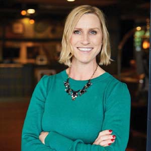 A portrait of Kate Thompson. She is a white woman with shoulder-length hair and a teal blouse
