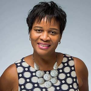 A portrait of Lorine Charles-St. Jules. She is a black woman with short straight hair and a black and white patterned blouse