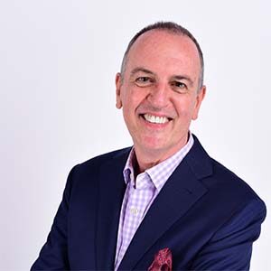 A portrait of Martin B. Jones. He is a balding white man with a blue suit and purple plaid collared shirt