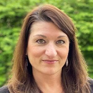 A portrait of Stephanie Harris. She is a white woman with straight brown hair and a black sweater