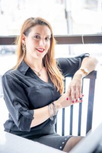 A portrait of Stephanie Jayko. She is a white woman with long reddish hair and a black collared shirt