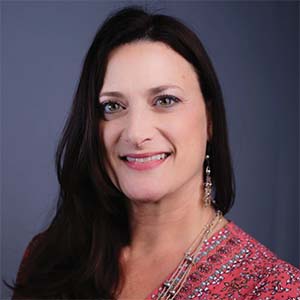 A portrait of Lauren Siring. She is a white woman with long dark hair and a patterned pink blouse