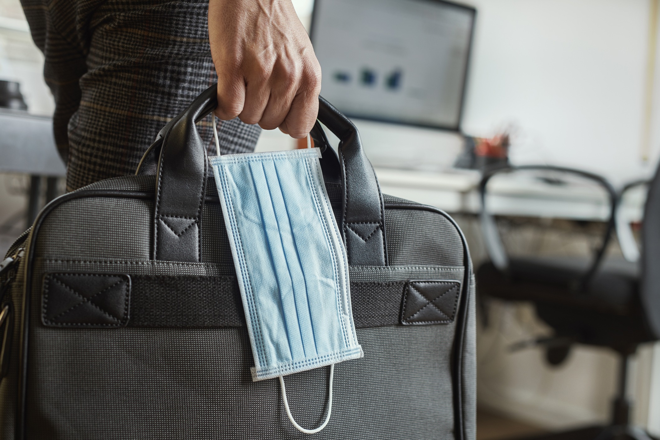 A man with a briefcase and a mask in one hand