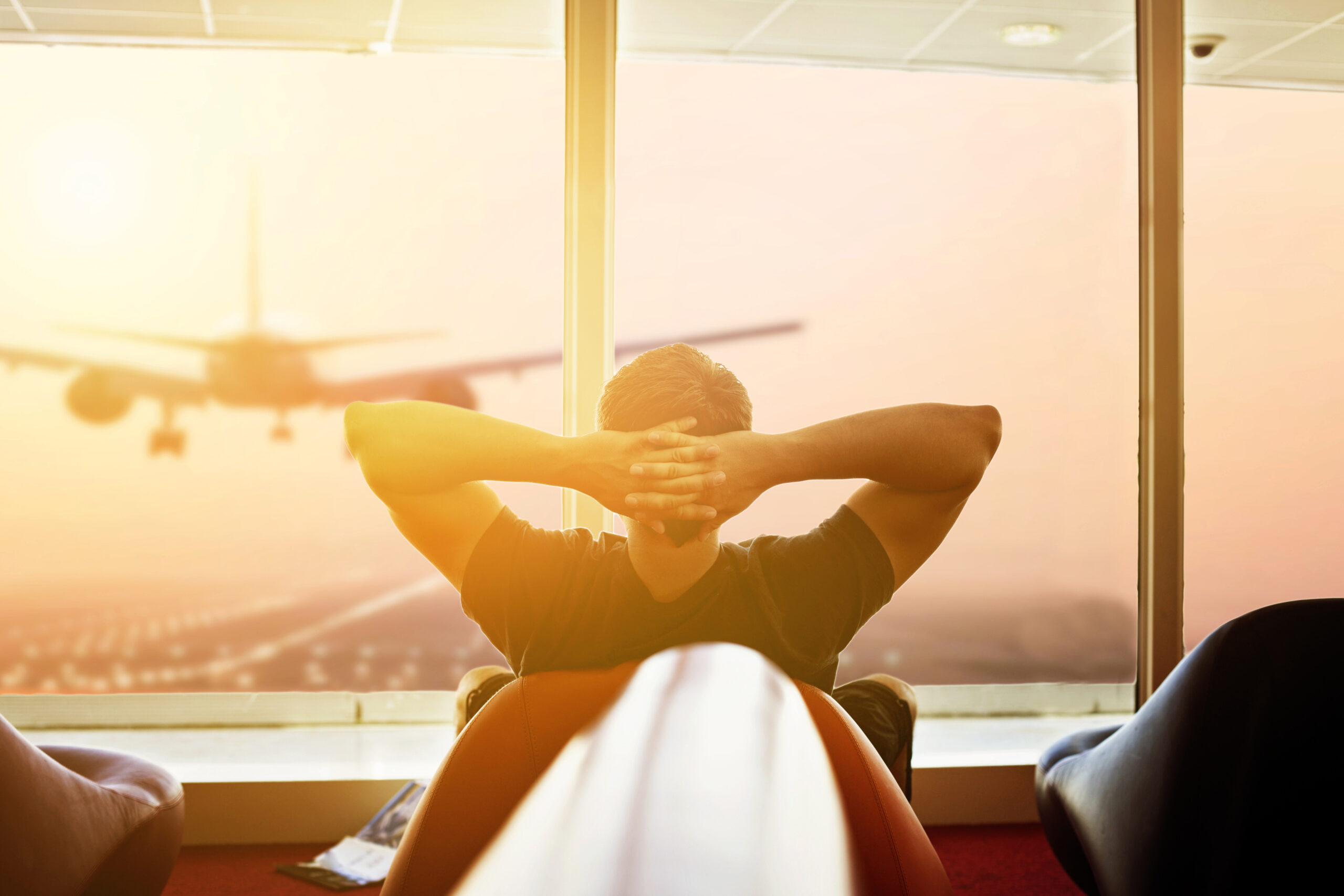 A man at the airport watching a plane take off