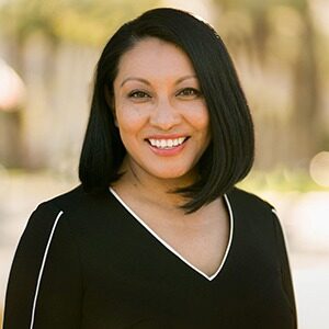 A portrait of Carolina Viazcan. She is a brown woman with shoulder-length black hair and a black blouse.