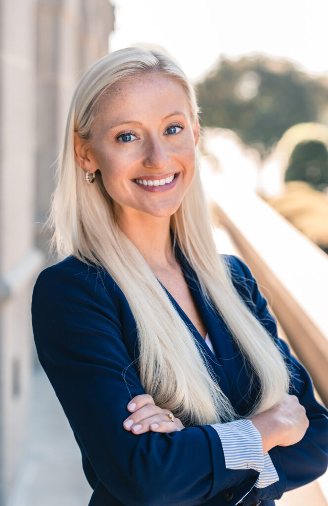 A portrait of Mallory Snyder, a young white woman with long blond hair and a dark suit jacket.
