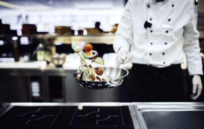 A stock image of a chef tossing vegetables in a pan