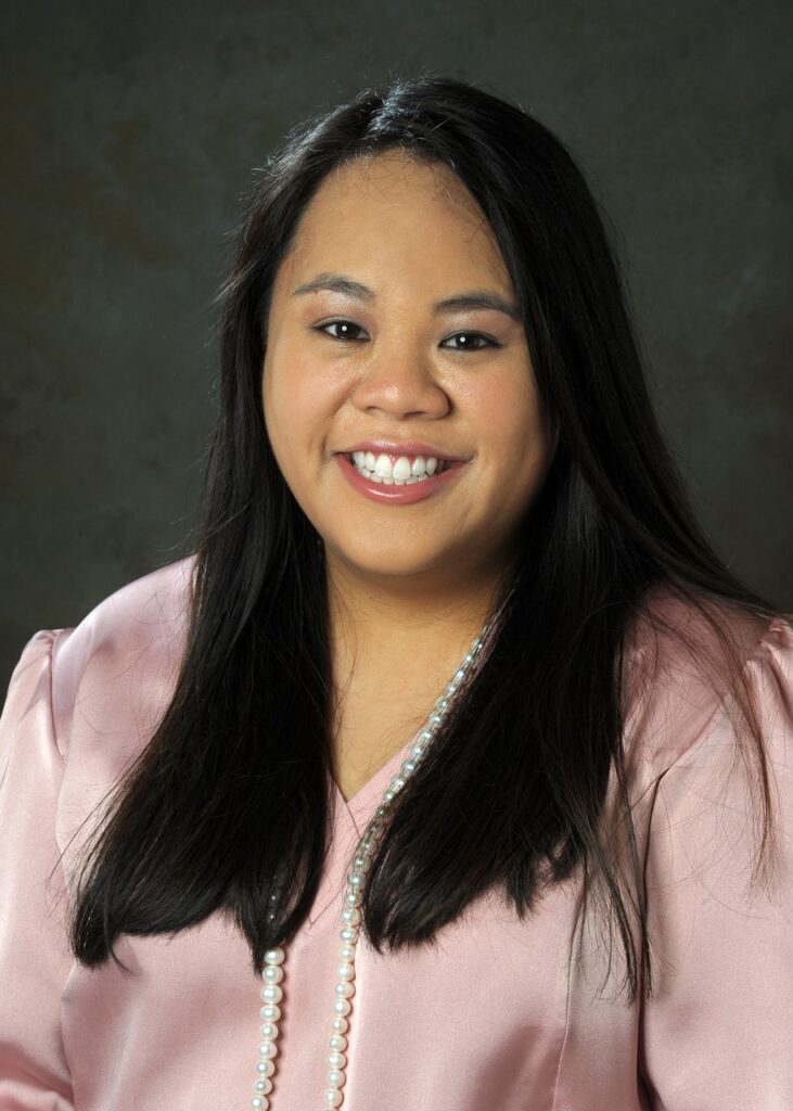 A portrait of Dani Keller, a young Asian woman with long dark hair and a pink blouse.