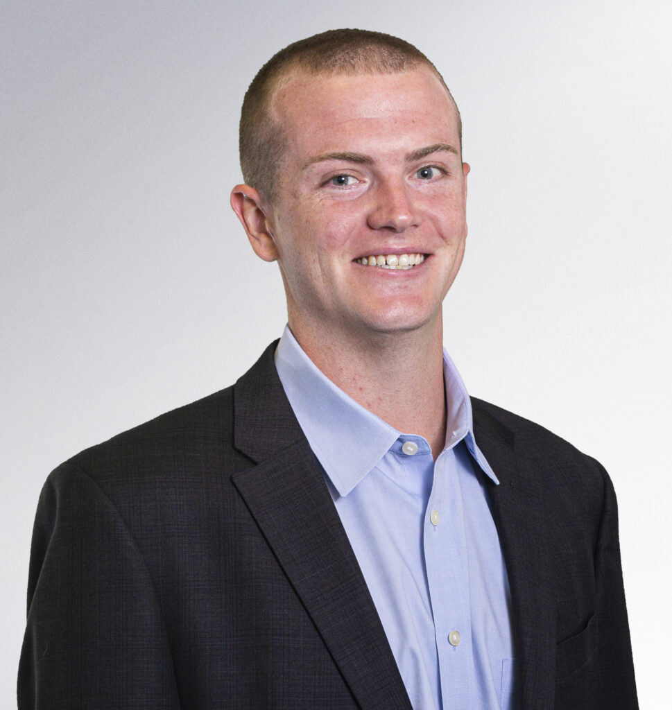 A portrait of Jonathan Walker, a young white man with short red hair and a black suit jacket.