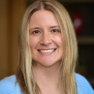 A portrait of Natalie LaVire. She is a blond white woman with a light blue sweater.