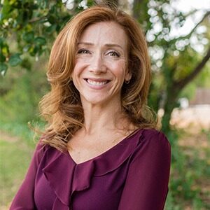 A portrait of Sezin Kutlu. She is a white woman with red hair and a purple blouse.