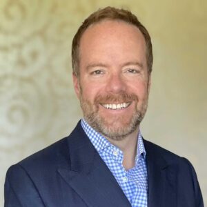 A portrait of Stephen D. Pickett, author of this article and chief strategy officer at a communications company. He is a white man with short brown hair and a dark blue suit.