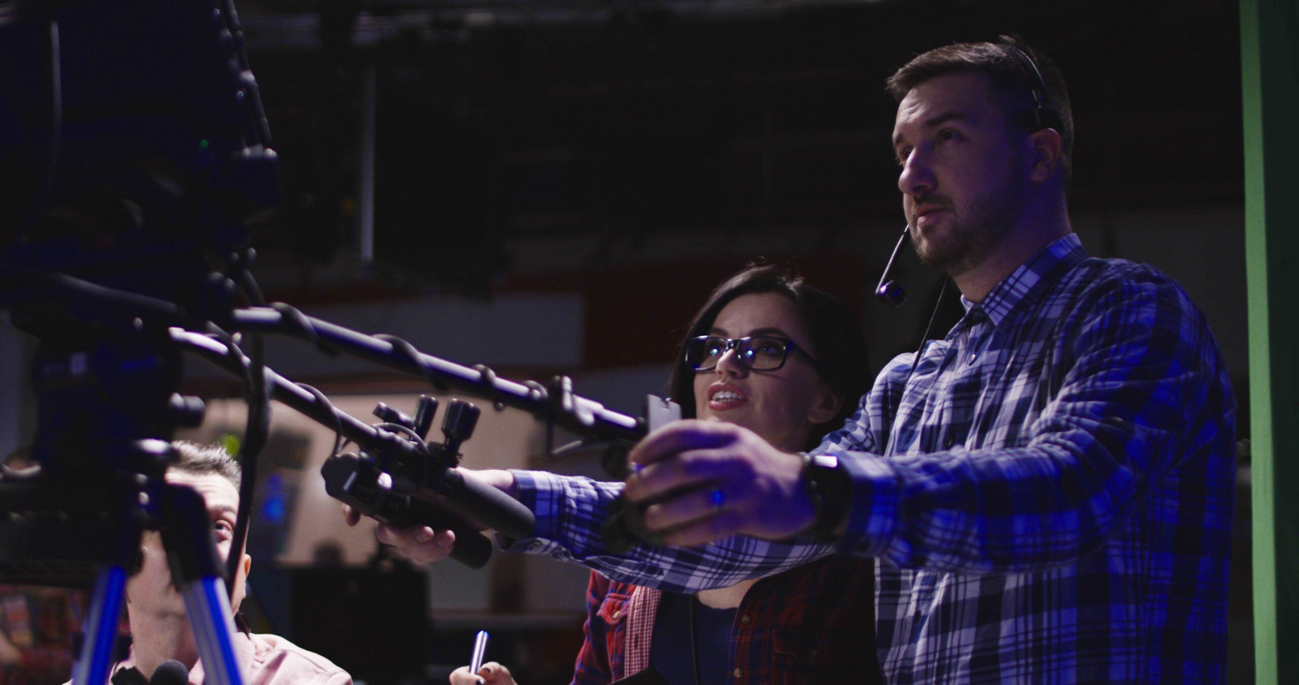 A cameraman and female director are watching the monitor of an out-of-frame camera.