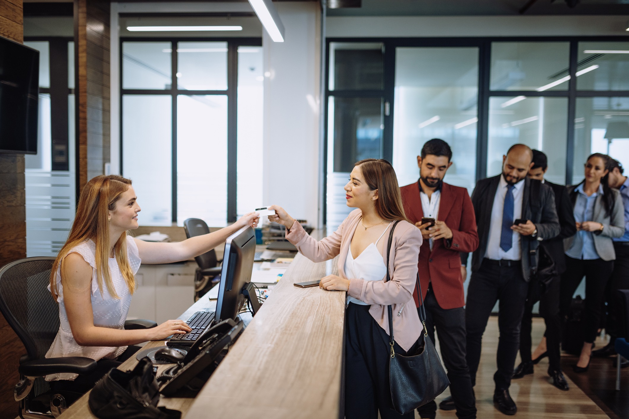 A group of people checking into a hotel with a receptionist.