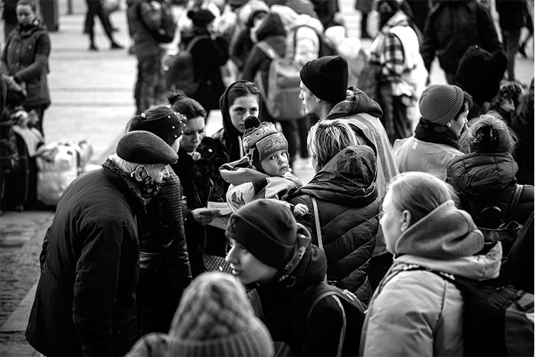 black and white image of crowd, one woman is holding a small child