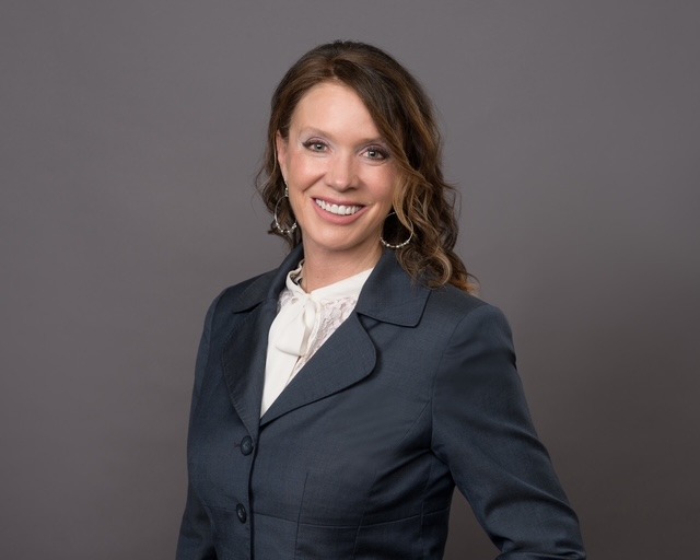 Woman in dark grey blazer and white shirt