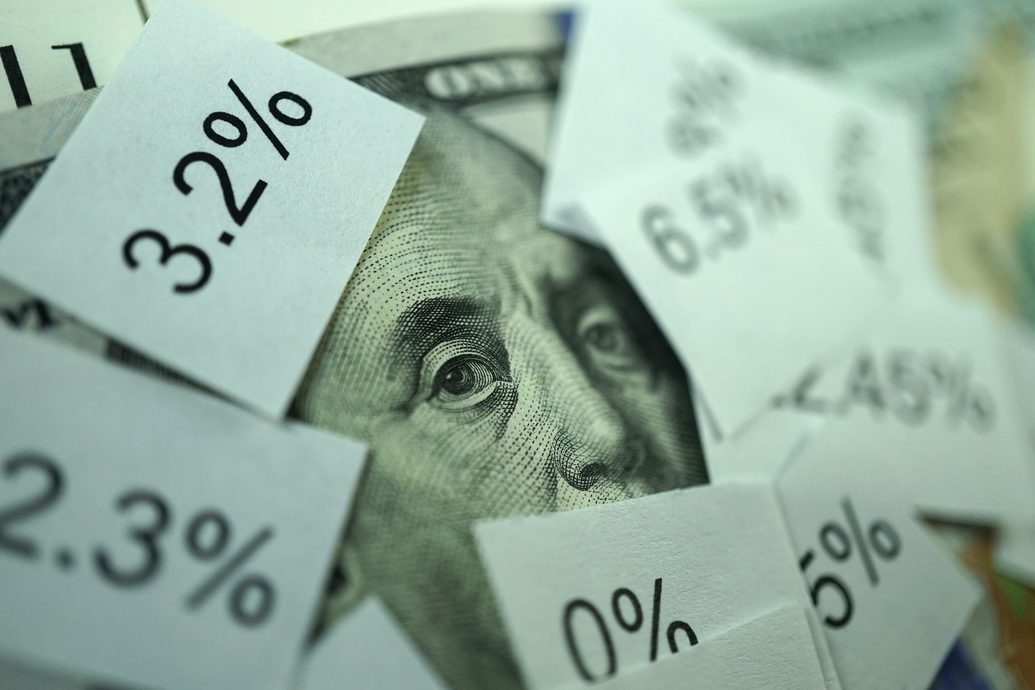20 dollar bill zoomed in on benjamin franklin's face surrounded by cards with rising interest rates