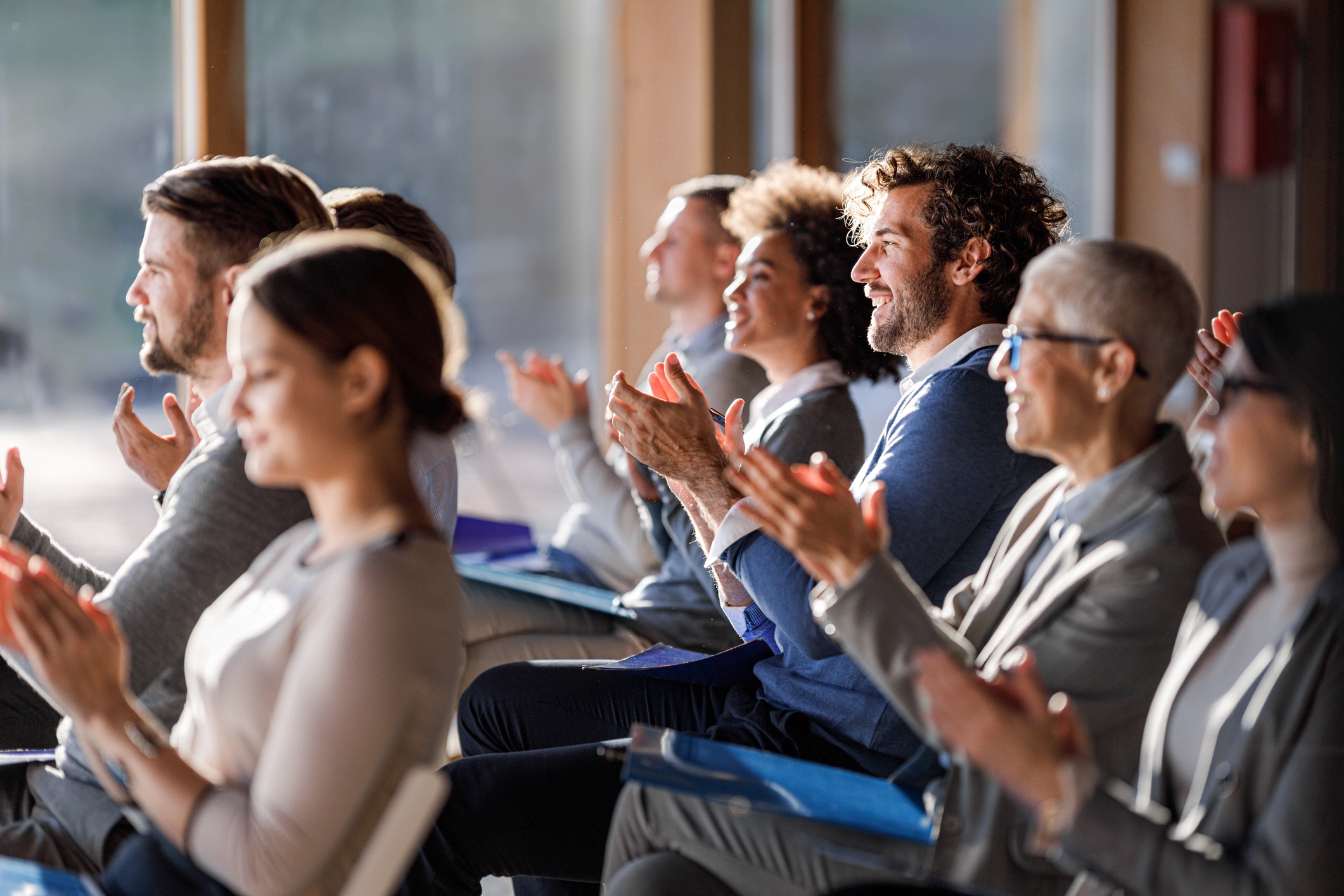 Large group of happy entrepreneurs applauding on a seminar at a convention