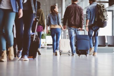 A group of passengers with roller bags walking in an airport terminal to their travel destinations