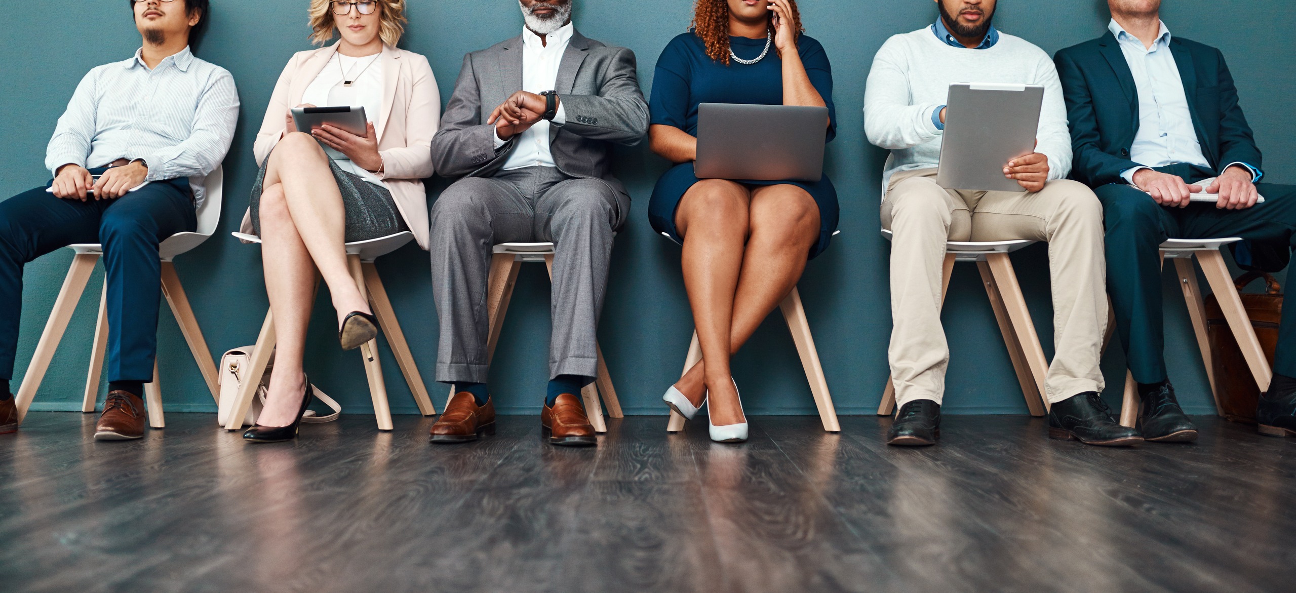 six businesspeople waiting sitting next to each other and waiting