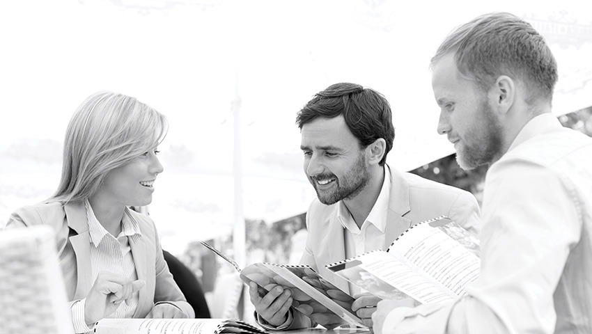 black and white photo of three businesspeople at restaurant looking at menu