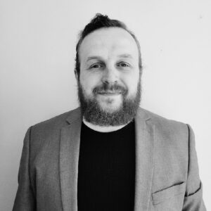 black and white photo of derrick erwee wearing grey blazer and black t-shirt