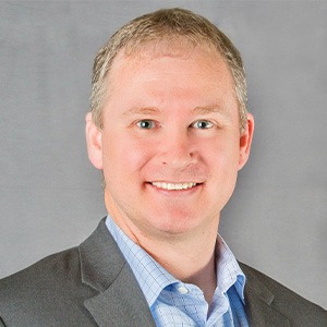 john mcpartlan wearing blue dress shirt and grey blazer