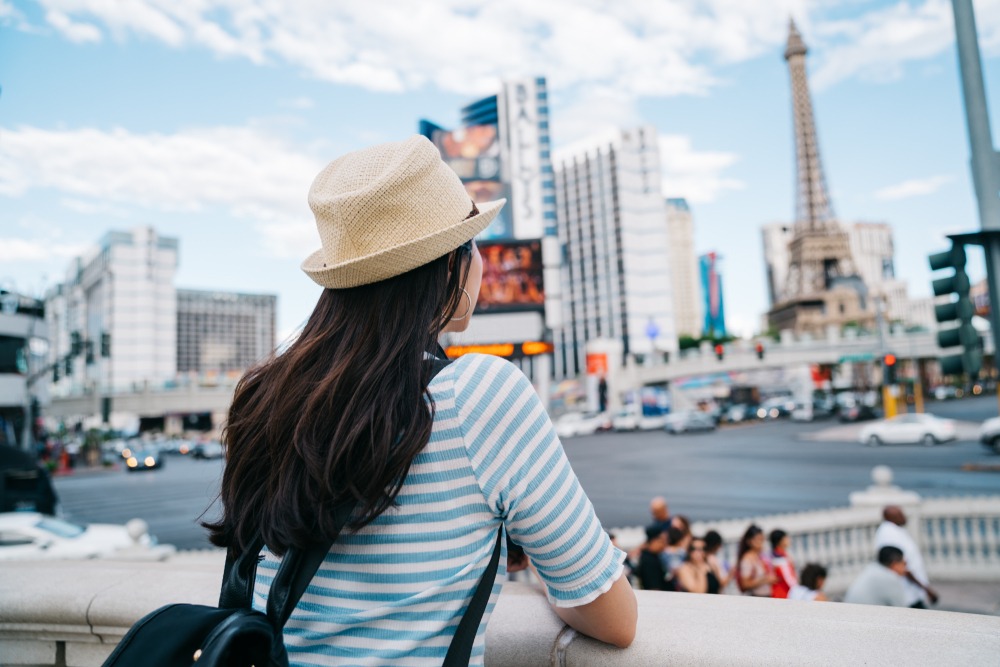 back view of a lady with straw hat watching the tower standing on las vegas strip sidewalk
