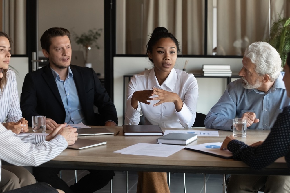 Diverse multicultural employees sit at conference desk listen to young asian woman