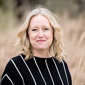 woman standing in field, wearing black shirt with white vertical lines