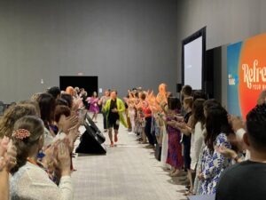 various people clapping as someone walks down runway