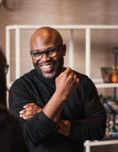 man wearing black long sleeve button up shirt, smiling