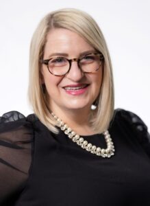 woman wearing pearls and black dress shirt with long mesh sleeves