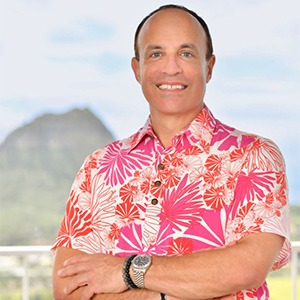 man folding arms, wearing pink floral shirt
