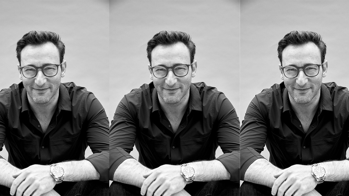 image of man sitting down, wearing button up shirt with top two buttons undone