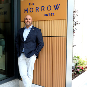 man leaning on wall, wearing blue suit