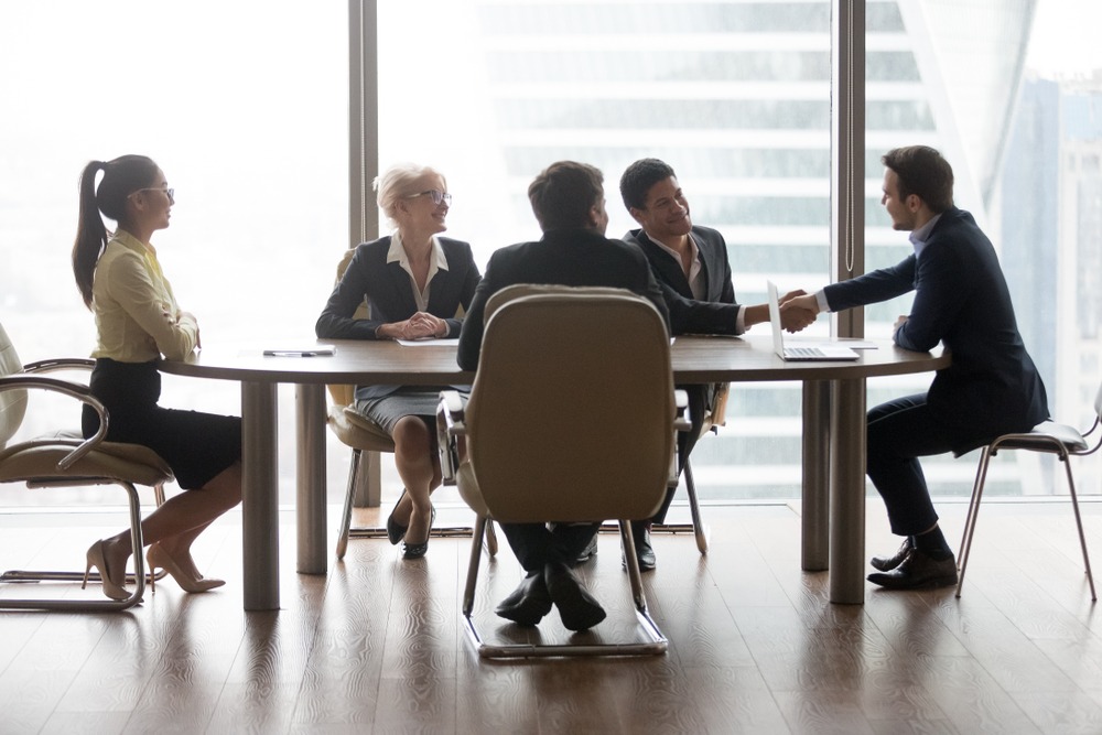 business people sitting at meeting in conference room and shaking hands