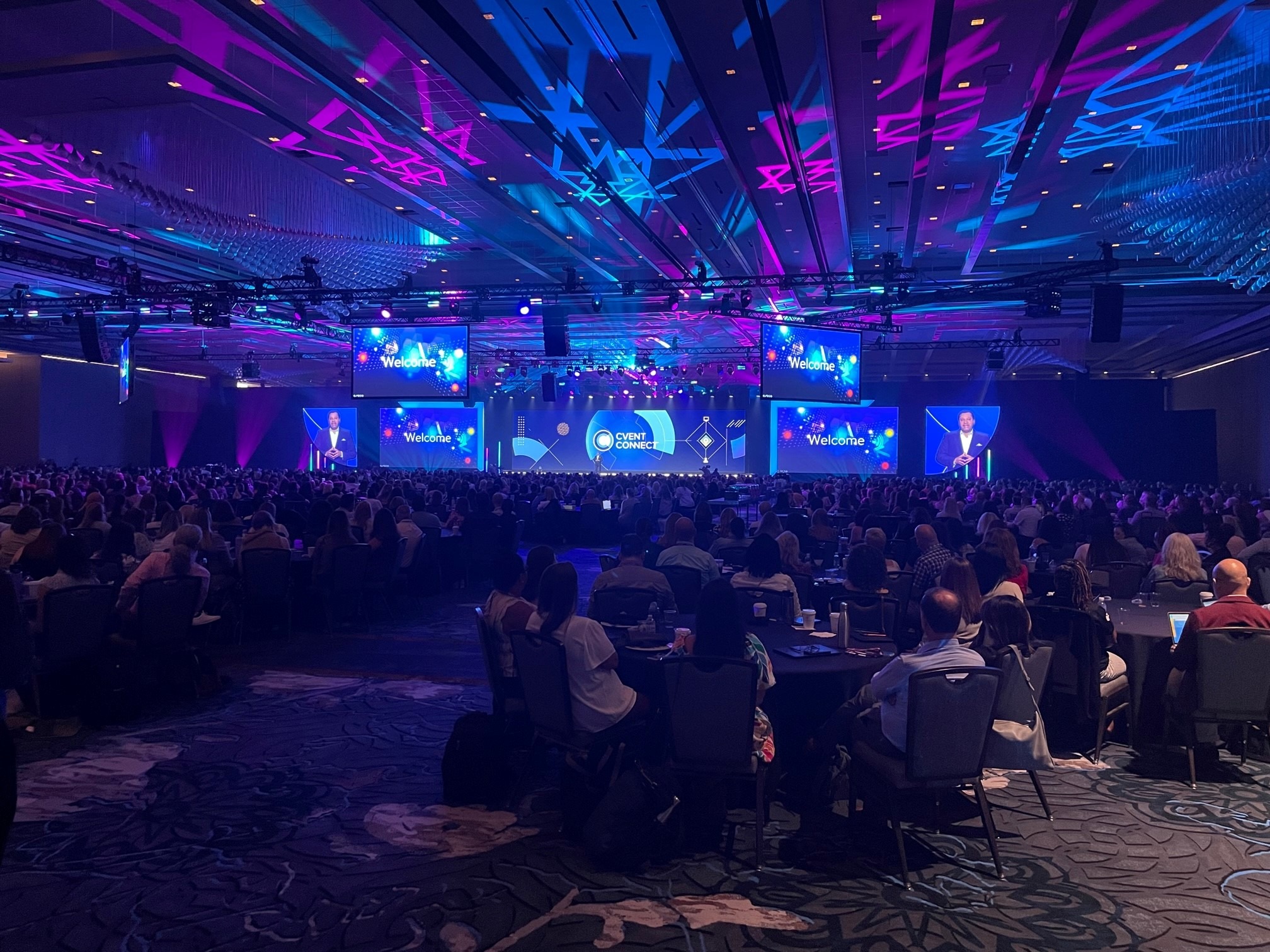 person on stage talking to large room of people