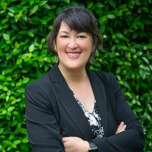 A woman in a black suit smiles into the camera