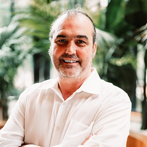 A man in a white shirt smiles into the camera